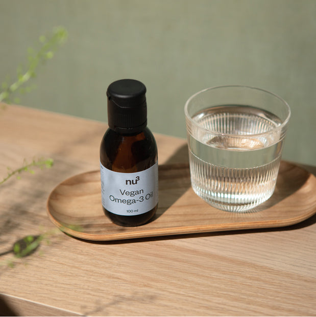 nu3 Omega-3 Öl vegan mit einem Glas Wasser