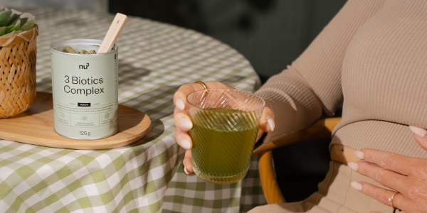Frau mit 3 biotics complex im Glas und Hand auf dem Bauch