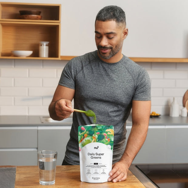 Mann mit Löffel Greens und einem Glas Wasser