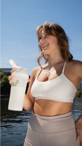 Frau im Sport-Outfit hält einen nu3 Shaker