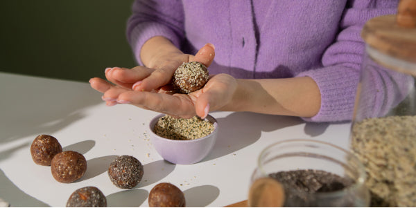 Frau formt Energyballs aus Teig