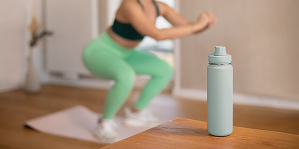 Flasche auf einem Tisch mit einer Person im Hintergrund, die Sport macht