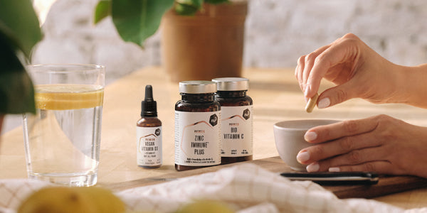 nu3 Premium Vitamin D, Zinc und Vitamin C mit einem Glas Wasser und Händen