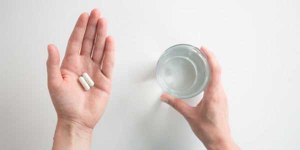 Zwei Kapseln Redcare Magnesium + Calcium + Vitamin D3