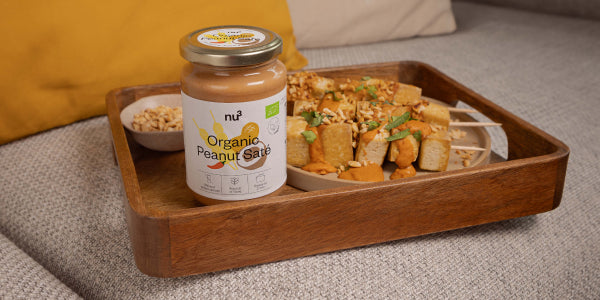 Glas mit Erdnuss-Saté-Sauce & Tofu-Spießen auf einem Tablett